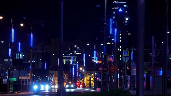 Street of a night city with moving cars along street lamps with a skyscraper on the background, Ekaterinburg, Russia. Stock footage. Cars driving on the night road, time lapse.