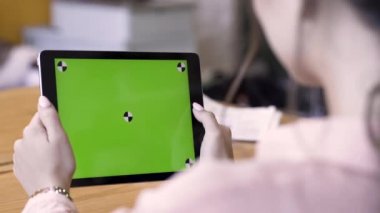 Esmer bir kadının yeşil ekranlı tablet kullanması, modern teknoloji kavramı. Stok görüntüleri. Kadın ipad 'i krom anahtarla tutuyor ve bir şeyler okuyor..