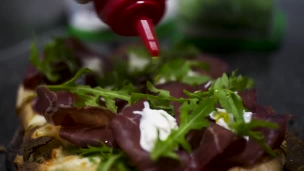 Close up para o bruschetta com jamon, queijo creme e folhas de arugula verdes frescos, conceito foodporn. Moldura. Delicioso lanche com pão, creme de queijo e verdura . — Vídeo de Stock