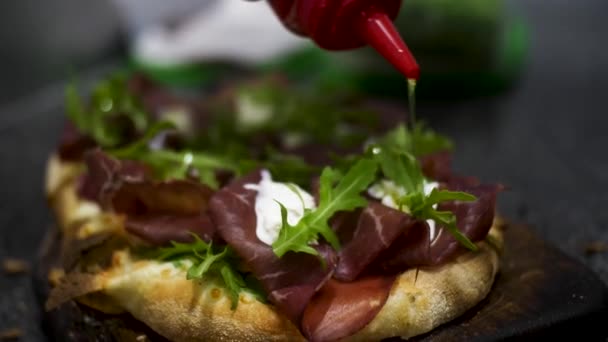 Close-up voor de Bruschetta met Jamon, roomkaas en groene verse rucola bladeren, foodporn-concept. Frame. Heerlijke snack met brood, roomkaas en groen. — Stockvideo