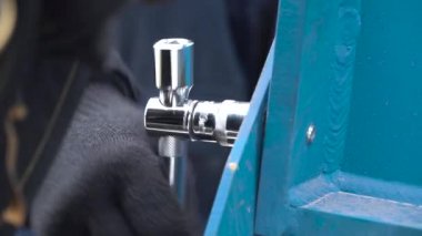 Erkek eli koruyucu eldivenler giyip, metal mavi yapıda bir İngiliz anahtarıyla sürgüyü gevşetmek için yaklaşın. Şarjör. Metal yapının sökülmesi.
