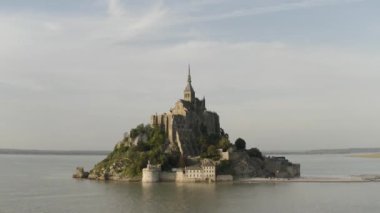 Mavi bulutlu arka planda denizle çevrili adadaki eşsiz tapınağın havadan panoramik görüntüsü. Başla. İnanılmaz Mont-Saint-Michel kalesi, Fransa.