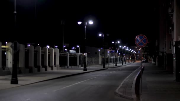 Leere Stadtstraße, nächtliche Szenerie in der Stadt mit Straßenlaternen auf schwarzem Himmelshintergrund. Archivmaterial. spätabendliche Straße in modernem Wohngebiet. — Stockvideo