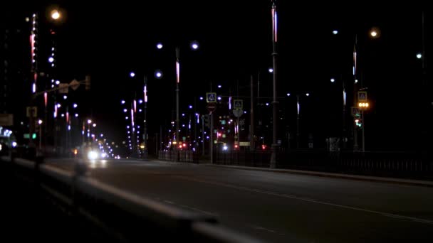 Éjszakai forgalom az úton, magányos autó az utcai lámpák mellett. Készletfelvétel. Éjszakai városi út utcai fények és mozgó autó sötét ég háttér. — Stock videók