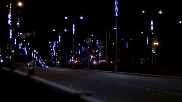 Ночной вид на пустую городскую дорогу с множеством огней по обе стороны дороги. Запись. Летняя ночная дорога освещена неоновым светом фонарей . — стоковое видео
