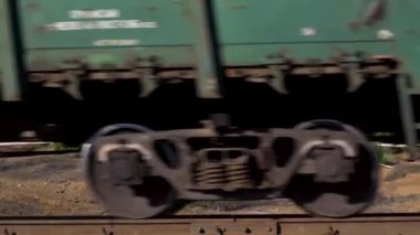 Raylar üzerinde hareket eden bir yük treninin yan görüntüsü ve arka planda güzel doğal bir manzara. Stok görüntüleri. Yeşil ağaçların ve dağların önündeki yük trenine yaklaşın..