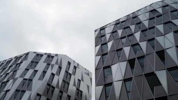 Vista inferior de edificio único moderno con ventanas en forma de triángulo de color negro sobre fondo cielo nublado brillante. Imágenes de archivo. Detalles arquitectónicos, fachada de cristal . — Vídeos de Stock
