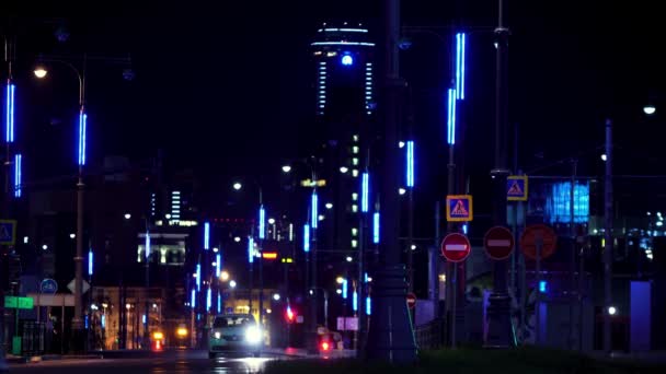 Éjszakai táj egy modern város tele neon fények autók mozognak az úton. Készletfelvétel. Éjszakai út világít sok neon utcai lámpák és a vezetés autók. — Stock videók