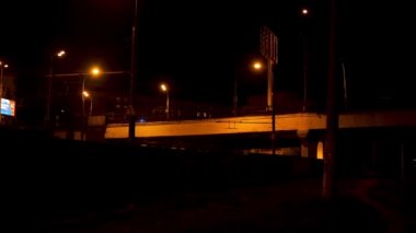 Gece köprüsü, siyah gökyüzü arka planında araba süren sokak ışıklarıyla aydınlandı. Stok görüntüleri. Şehir köprüsü hareket halindeki araçlarla sokak lambalarının altında..