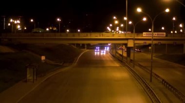 Siyah gökyüzü arka planında sürüş arabaları olan gece caddesi için hava aracı. Stok görüntüleri. Gece trafiği, geniş yol, köprü birçok sokak lambası ve hareket halindeki araçlarla aydınlandı..