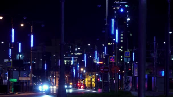 Paisaje nocturno de una ciudad moderna llena de luces de neón con coches moviéndose por la carretera. Imágenes de archivo. Carretera nocturna iluminada por muchos faroles de neón y coches de conducción . — Vídeos de Stock