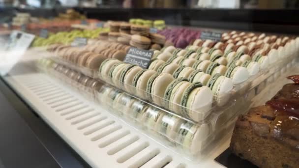 Assortment of colorful traditional French macarons laying in rows on market counter, food concept. Action. Colorful cakes on the counter of the store, sweet meringue-based confection, close up. — Stock Video