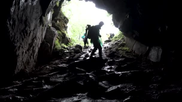 Młody odkrywca stojący w jaskini ze sprzętem wspinaczkowym gotowym do akcji, podróżującym i ekstremalnym konceptem. Materiał filmowy. Widok z wnętrza jaskini z wspinaczką. — Wideo stockowe