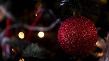 Bulanık, ışıl ışıl ve peri geçmişiyle süslenmiş Noel ağacı, mutlu noeller ve mutlu yeni yıl konsepti. Çerçeve. Kırmızı parlayan top ve fenerlerle aydınlatılmış çelenk için yakın..