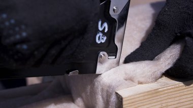 Ahşap kiriş, ev bina konsepti ne akonstrüksiyon zımba ile koruyucu cam dikiş ısı yalıtım malzemesi işçi eller için yakın. Klip. Profesyonel marangozluk işi.