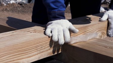 Birbirine bağlanmış ahşap kirişlere dokunan koruyucu camda işçi elleri için yakın çekim, ev inşa konsepti. Klip. Profesyonel marangozluk işi.