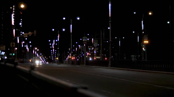 Tráfico nocturno en la carretera, coche solitario conduciendo a lo largo de las farolas. Imágenes de archivo. Calle de la ciudad nocturna con luces de calle y coche en movimiento sobre fondo de cielo oscuro . — Foto de Stock