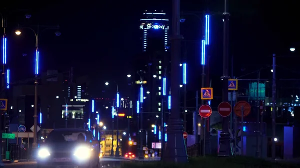 Arabaları yolda ilerleyen neon ışıklarla dolu modern bir şehrin gece manzarası. Stok görüntüleri. Gece yolu birçok neon sokak lambası ve sürücü arabasıyla aydınlandı.. — Stok fotoğraf