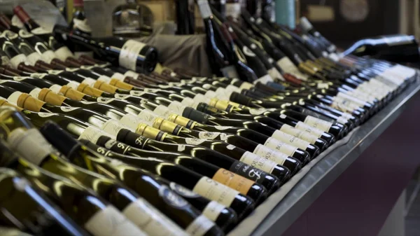 Close-up para fileiras de garrafas de vinho na loja, conceito de álcool de luxo. Acção. Garrafas de vidro de vinho tinto e branco em prateleiras de madeira em coleção adega privada . — Fotografia de Stock