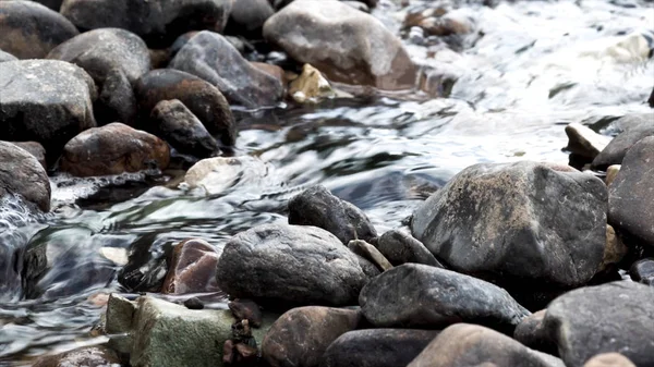 用干净的冷水和灰色的石头关上一条小河。 行动。 透明的冷水流过风景如画的潮湿岩石. — 图库照片