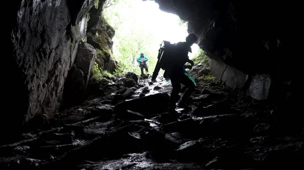 Jonge ontdekkingsreiziger staat in een grot met klimuitrusting klaar voor actie, reizen en extreem concept. Voorraadbeelden. Uitzicht vanuit de grot met klimmer. — Stockfoto