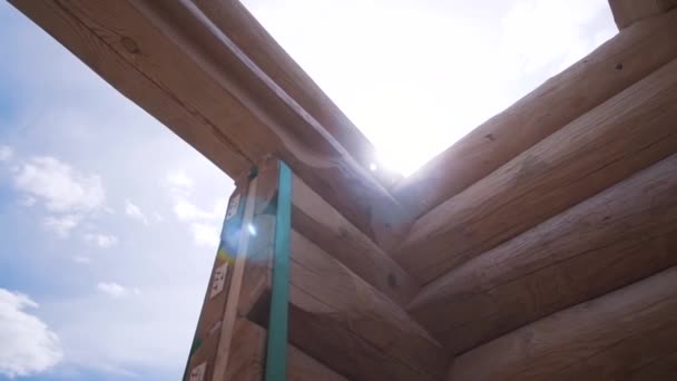 Primo piano di struttura della casa di legno contro il cielo nuvoloso azzurro in giorno soleggiato estivo. Clip. Processo di costruzione di case in legno — Video Stock