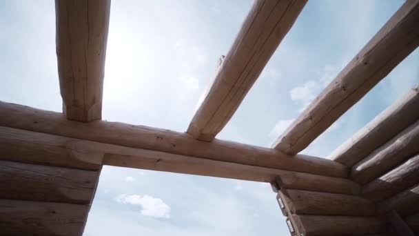 Detailní záběr záběru dřevěného domu proti modré oblačné obloze v letním slunném dni. Klip. Dřevěný dům stavební proces — Stock video