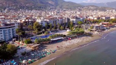 Şehrin arka planında yüzme havuzları olan tatil köyü manzarası. Şarjör. Tatilcilerin yaz tatillerinde tatil yaptığı panoramik şehir plajı manzarası