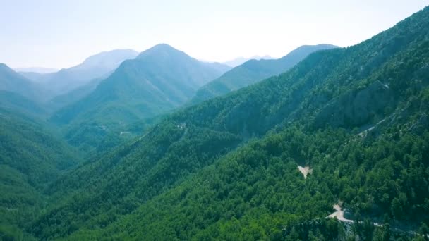 Вид сверху на красивый зеленый пейзаж гор. Клип. Красивые горные долины с зеленым покрытием на фоне неба. Дороги, проходящие через горные долины, идеально подходят для летних путешествий — стоковое видео