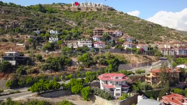 Toeristische inscriptie liefde stad. Een knip. Bovenaanzicht van de toeristische inscriptie betekent liefde voor de stad. Inscriptie Ik hou van Alanya. Toeristische inscriptie Ik hou van Alanya stijgt op berg boven resort stad — Stockvideo