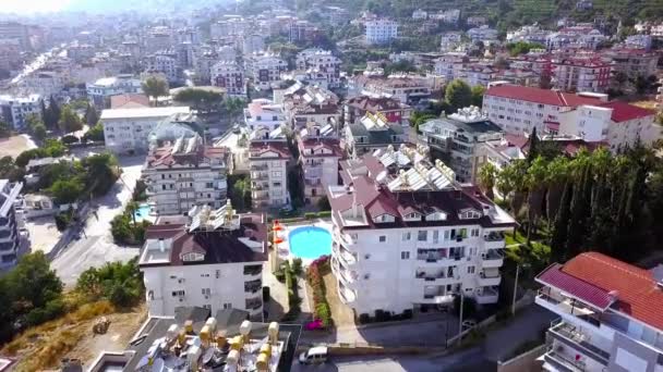 Κάτοψη των όμορφων ξενοδοχείων με πισίνα στο φόντο της πόλης. Κλιπ. Top view of beautiful modern hotels in resort town το καλοκαίρι — Αρχείο Βίντεο