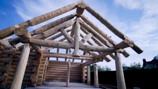 Quadro de casa de campo de madeira em construção a partir de troncos. Clipe. Construção de casa de madeira no início da construção no fundo do céu azul — Vídeo de Stock