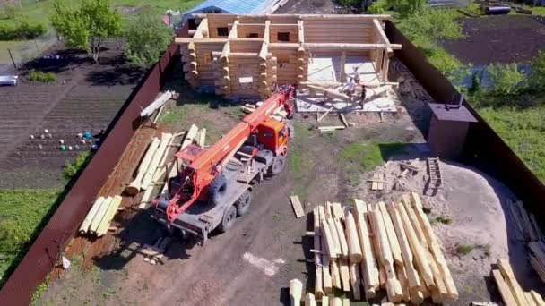 Вид зверху на дерев'яний будинок, що будується. Кліп. Вид зверху на сільську землю, на якій будується дерев'яний будинок. Будівництво заміського дерев'яного будинку з краном на місці — стокове відео