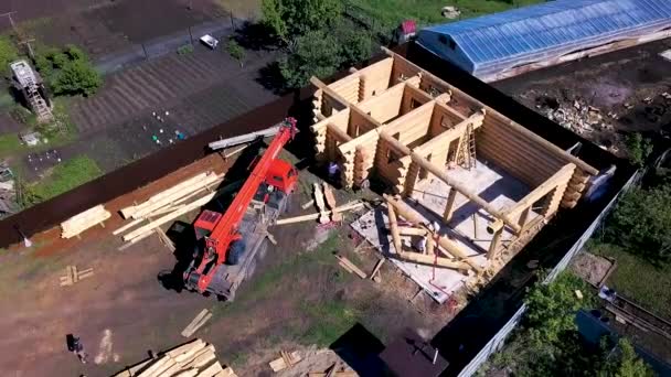 Vista superior da casa de madeira em construção. Clipe. Vista superior de terra de país em que construção de casa de madeira. Construção de casa de madeira do campo com guindaste no local — Vídeo de Stock