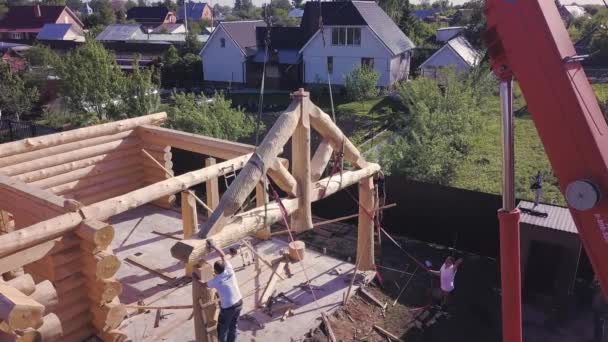 Instalace střešních trámů dřevěný dům. Klip. Horní pohled na stavbu dřevěného domu s dělníky a jeřábem na staveništi. Montáž fasádního rámu dřevěné střechy — Stock video