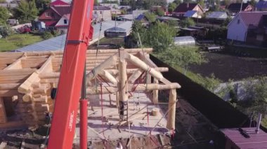 Çatı kirişleri ahşap ev. Şarjör. İnşaat alanında işçilerin ve vinçlerin bulunduğu ahşap evin en üst görüntüsü. Ahşap çatının ön cephe çerçevesinin kurulumu