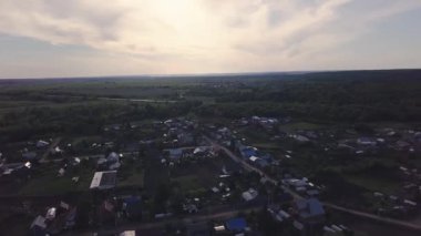 Yazın gökyüzü ve ufukta kır evleri olan şehrin en iyi manzarası. Şarjör. Yeşil ağaçlar ve ufka uzanan tarlaların arka planında köyü olan güzel bir kırsal bölge.