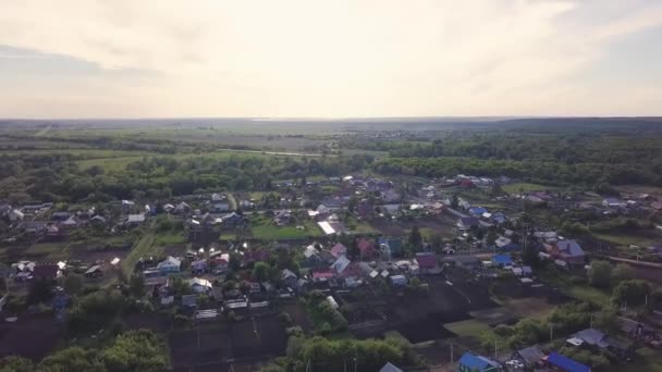 Vista superior de la ciudad con cabañas en el horizonte con el cielo en verano. Clip. Hermoso campo con pueblo en el fondo de árboles verdes y campos que llegan al horizonte — Vídeo de stock