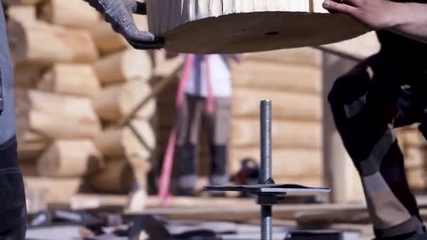 Close-up werknemers werken met logboeken op de bouwplaats. Een knip. Bouwers ingesteld log op compensator krimp van hout op de achtergrond van bouwwerkzaamheden — Stockvideo