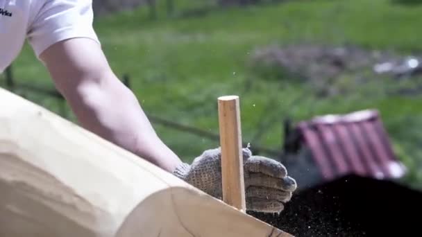 Een arbeider die houten pin hamert. Een knip. Close-up van de werknemer op het dak van houten huis hameren houten pin. Bouwer werkt met hamer op dak van landhuis — Stockvideo