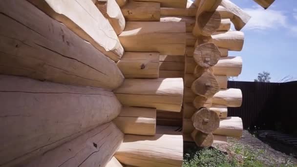 Costruzione di una casa di legno. Clip. Parete di casa di legno di tronchi tagliati in processo di costruzione. Parte esterna del muro con tronchi sporgenti di casa di campagna in legno — Video Stock