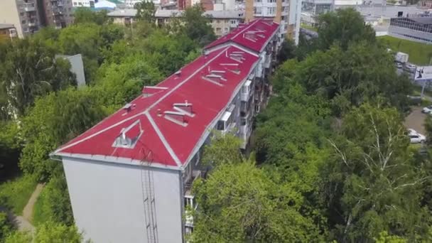 Top kilátás nyílik a piros tető többszintes lakóépület. Készletfelvétel. A többszintes lakóépület vörös tetőjének tetejére néző — Stock videók