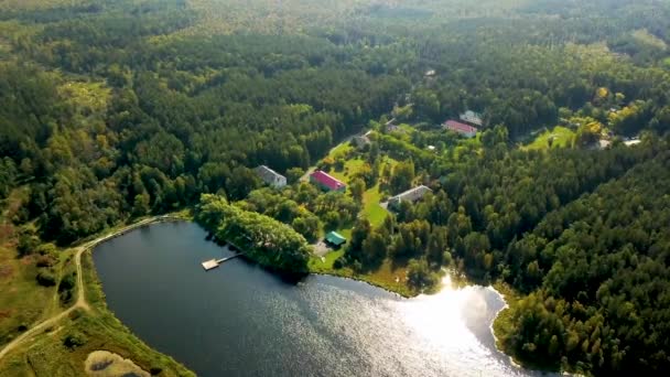 Старый загородный курорт в лесу у озера. Запись. Вид на живописный центр отдыха, расположенный на берегу озера. Прекрасный отдых в сельской местности в лагере в солнечную погоду — стоковое видео