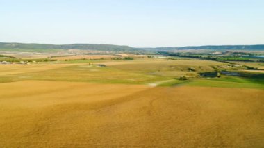 Ufuktaki köyün arka planındaki sarı tarlaların üst görüntüsü. Vuruldu. Uzakta tarım sarı tarlaları ve köyü olan güzel bir manzara.
