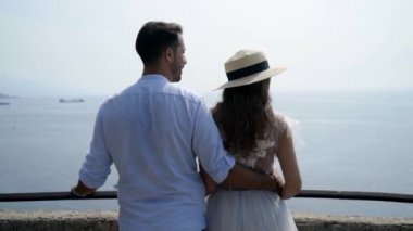Denize bakan genç bir çift. Başla. Balayındaki yeni evliler sahilde dinleniyor. Güzel yeni evliler kıyıda durup deniz ufkuna bakıyorlar.