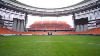 Futbol sahası olan ve ayakta duran bir stadyum. Başla. Bir sürü boş standı ve yeşil sahası olan futbol stadyumunun içi. Futbol stadyumunun mimarisi içeride.