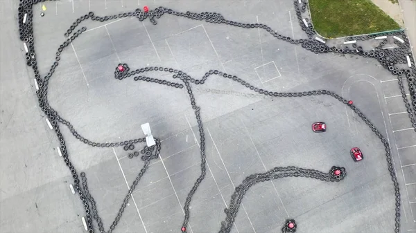 Aerial top view of the karting track made of old black car tires, motorsport concept. Media. Outdoors karting track situated on the concrete parking with driving red karts. — Stock Photo, Image