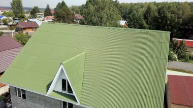 Covering green roof of village house. Stock footage. Top view of roof profiled green roof of house. New green roof of village house in summer clipart