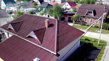 Kır evinin çatısının üst manzarası. Stok görüntüleri. Köyde çok güzel yeni bir ev var. Çatı kestanesi veya koyu kırmızı pahalı ve güzel görünüyor.
