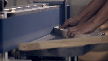 İnsanoğlunun yakın çekimi endüstriyel makinede ahşap ürünleri öğütüyor. Başla. Marangoz bant üretim makinesi için ahşap ürün parlatıyor